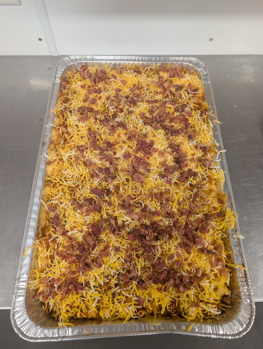 Loaded potato casserole tray topped with melted cheese and bacon