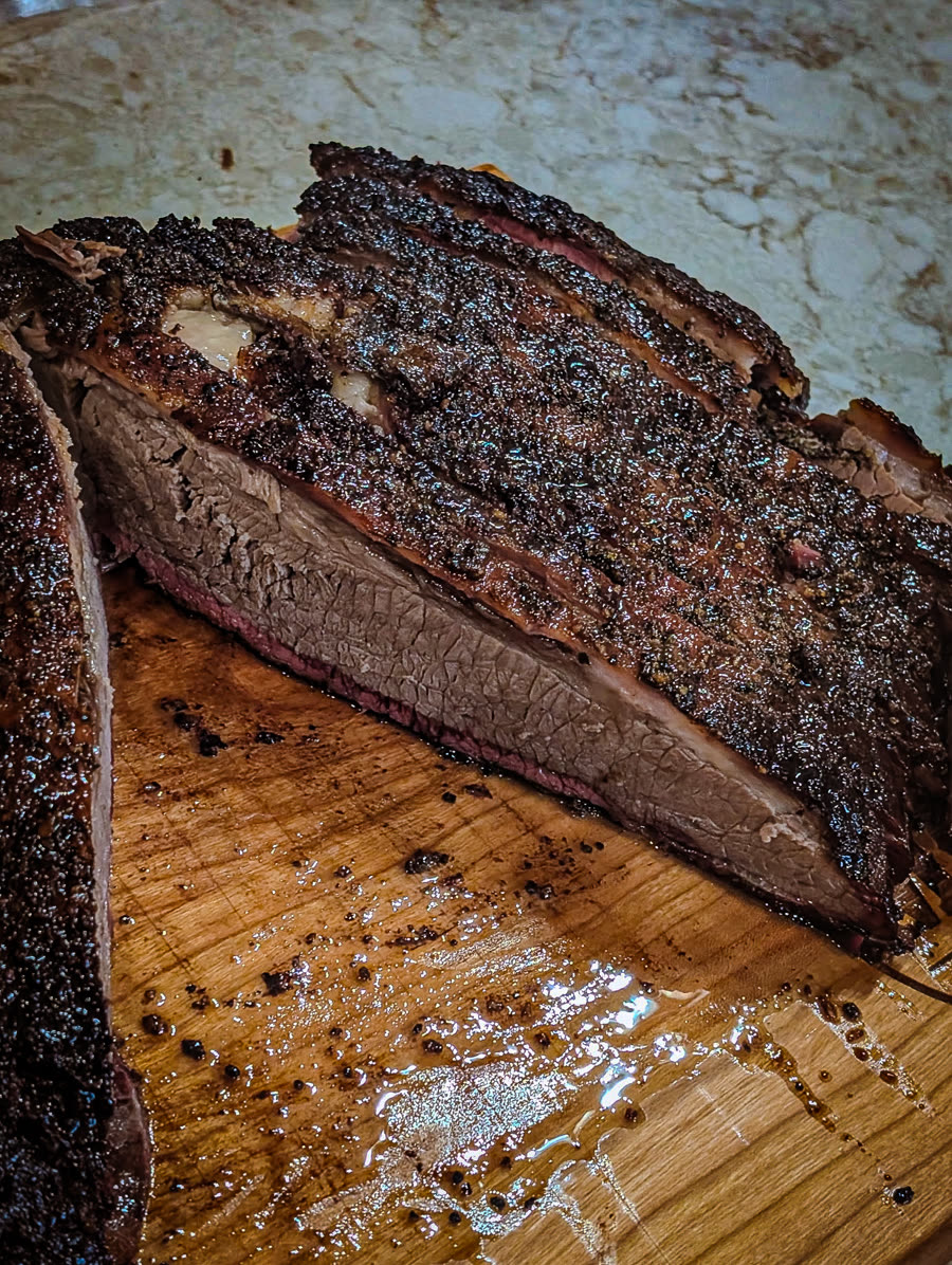 Smoked brisket cut open to show a juicy interior, pink smoke ring, and crusty bark