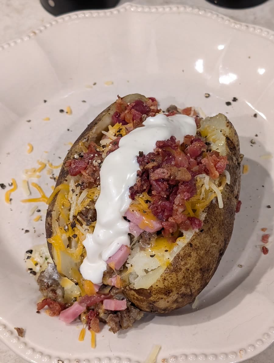 Loaded baked potato topped with cheese, bacon, sour cream and meat