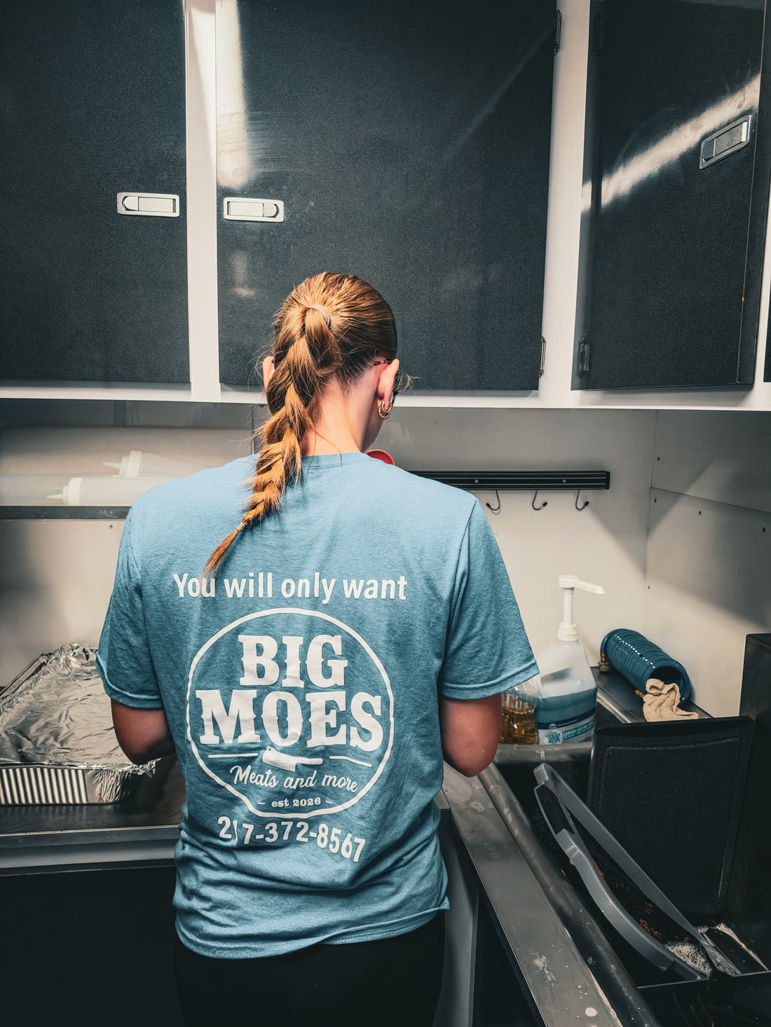 Big Moe's team member at work inside the trailer, wearing a Big Moe's t-shirt
