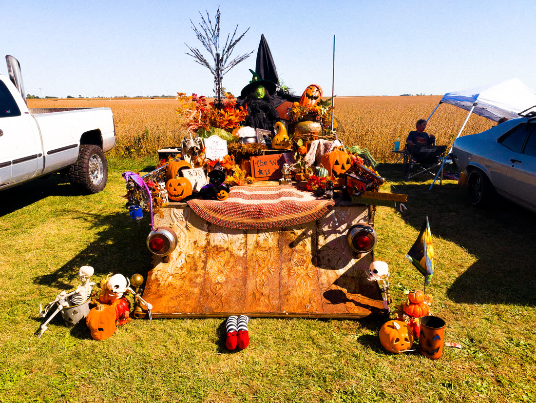 Truck bed piled with Halloween decorations, pumpkins, and a witch at the car show